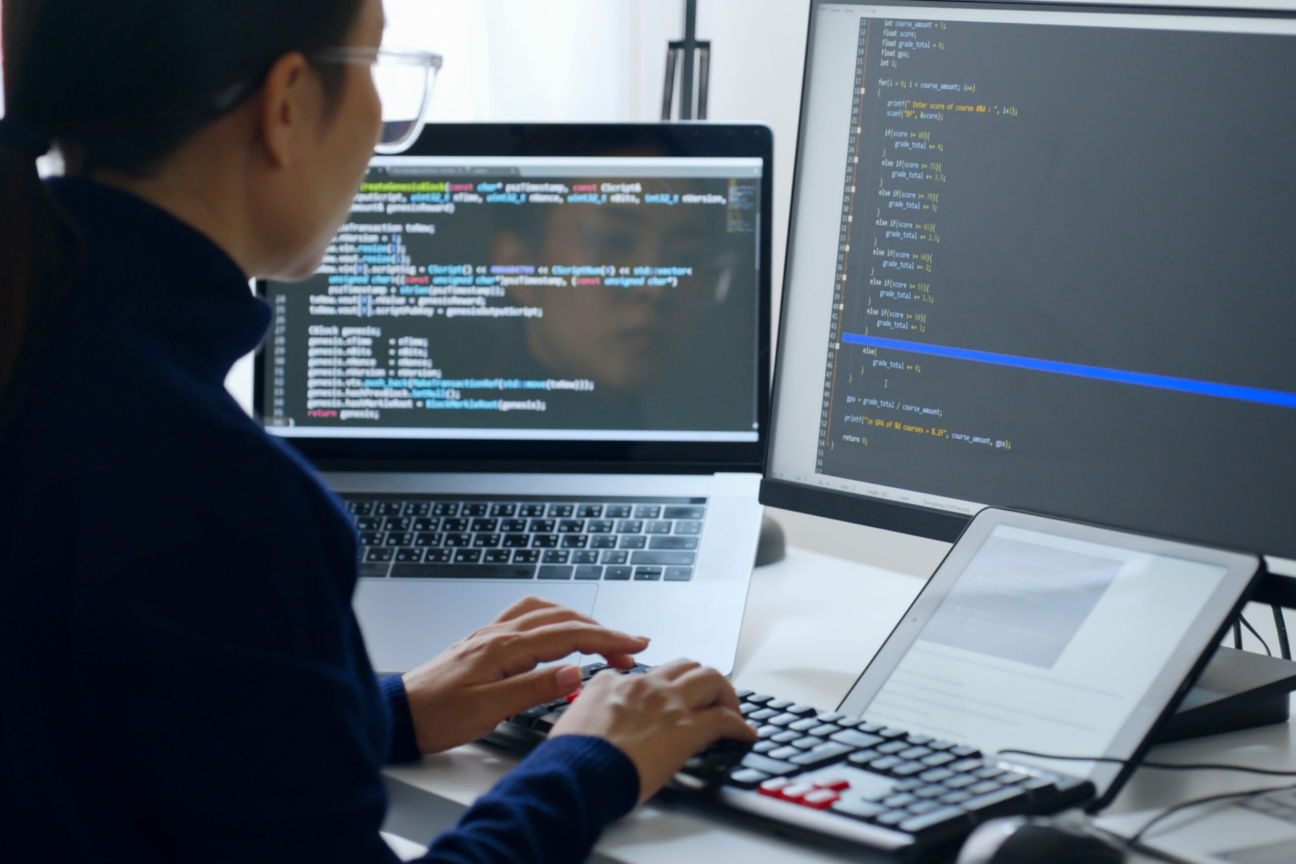 view of man looking at code on a monitor and laptop