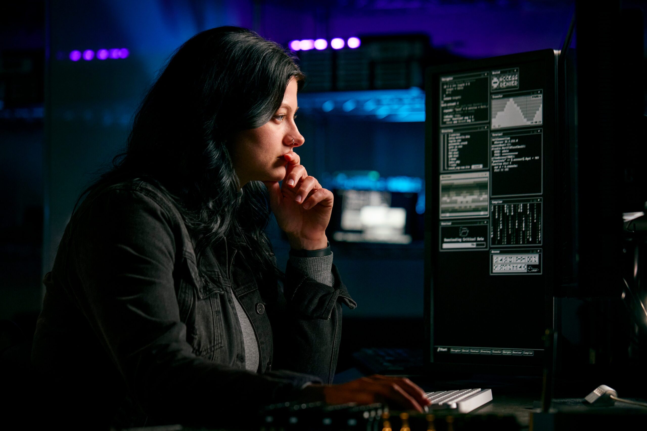 woman with dark hair focusing on computer screen in front of her appearing to be resting her chin on her hand while in thought